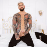 tattooed male Juan Lucho stroking his erect penis on bed